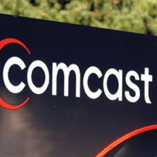 A comcast sign is shown in front of trees.